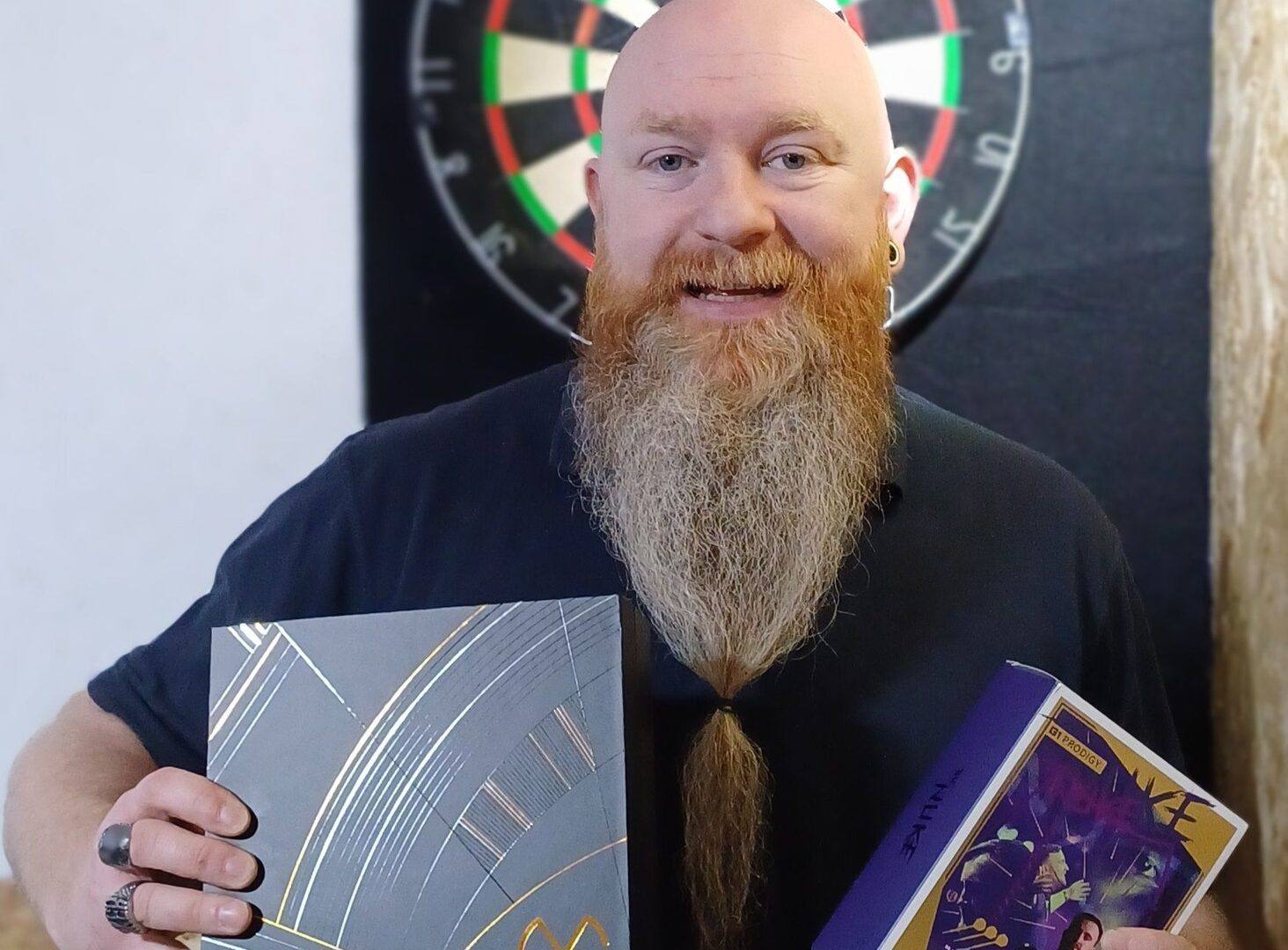 A happy winner holding the MvG Anniversary darts, celebrating their prize from The Darts Draw.