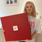 A smiling woman holding a large red LookFantastic advent calendar box with the LF logo in the center.